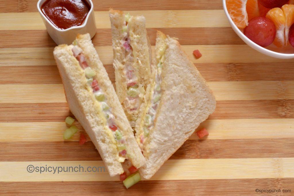 veggies stuffed cheese mayo sandwich is served with tomato ketchup and fruits