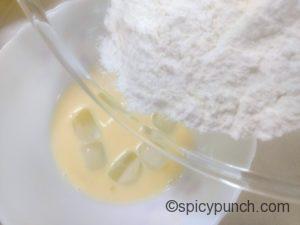 adding tempura flour to the beaten egg
