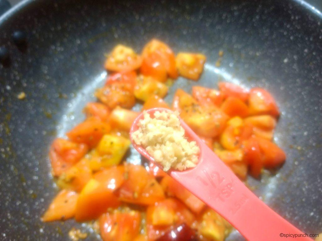 adding chopped ginger to the pan for making this bengali tomato chutney